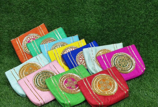 An assortment of colorful handbags with gota patch work displayed on a grassy surface.